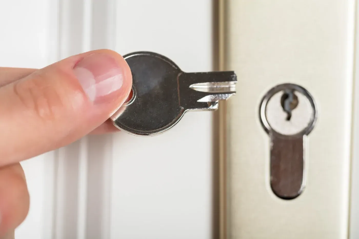 Una persona sostiene una llave en la mano delante de una puerta.