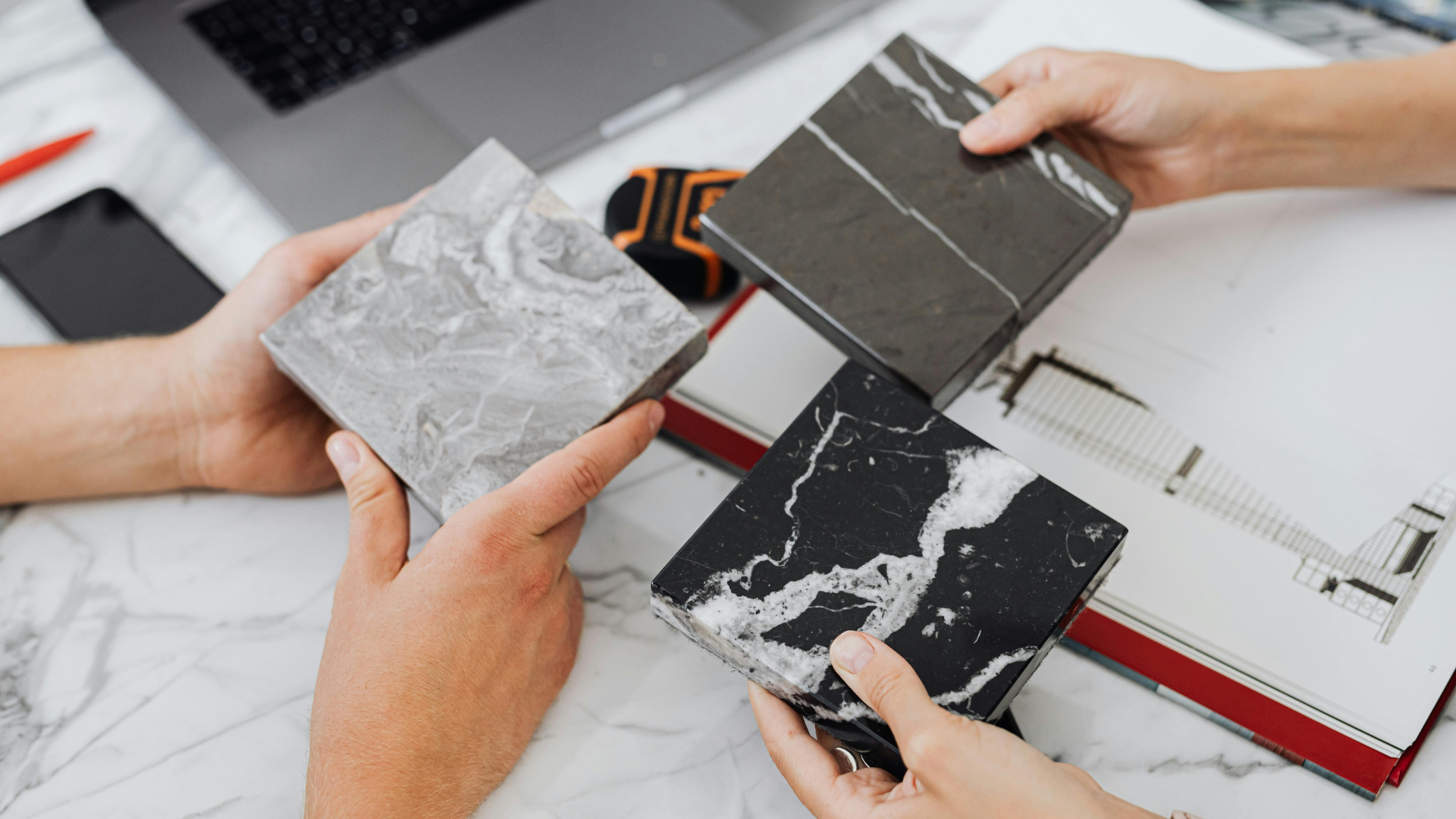 Des mains tenant des échantillons de comptoir en marbre ; comparant les motifs.
