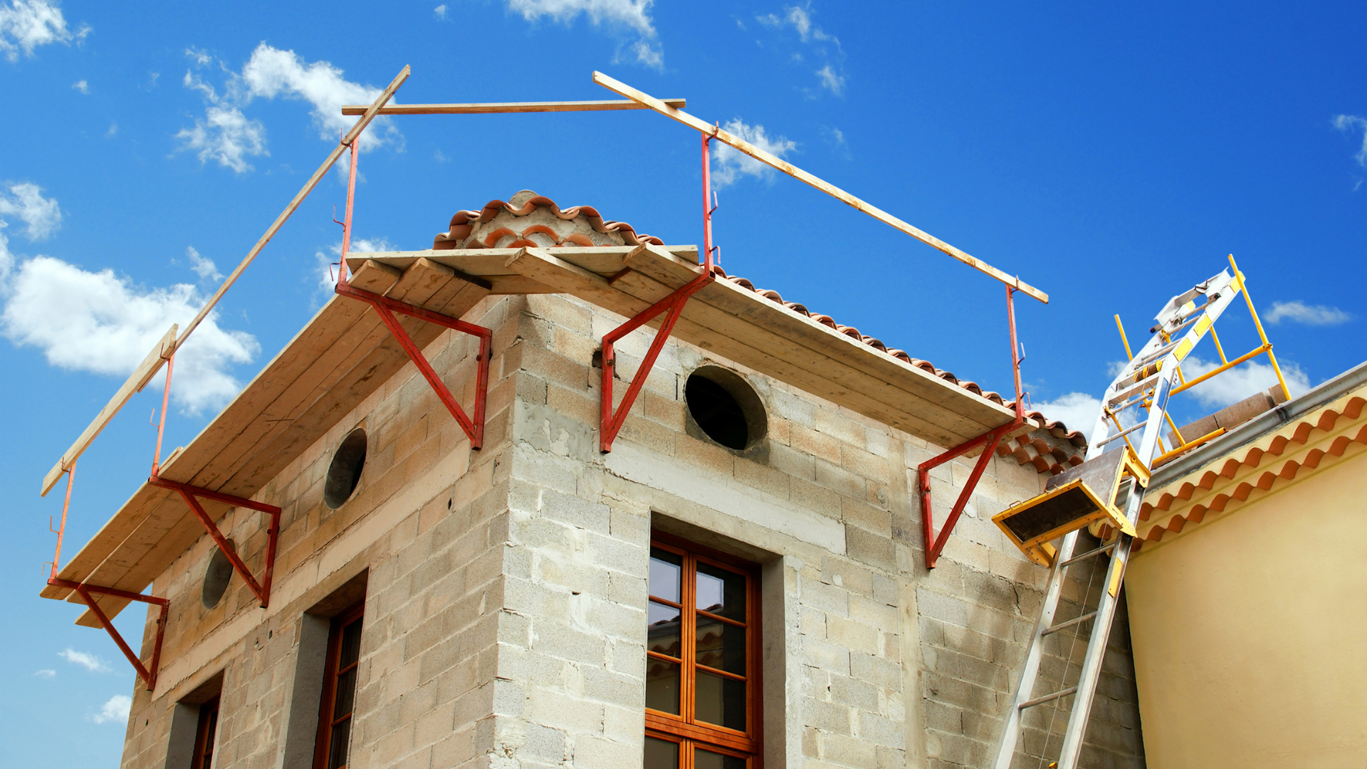 Échafaudage sur le toit d'un bâtiment en pierre, en construction ou en réparation, sur fond de ciel bleu.