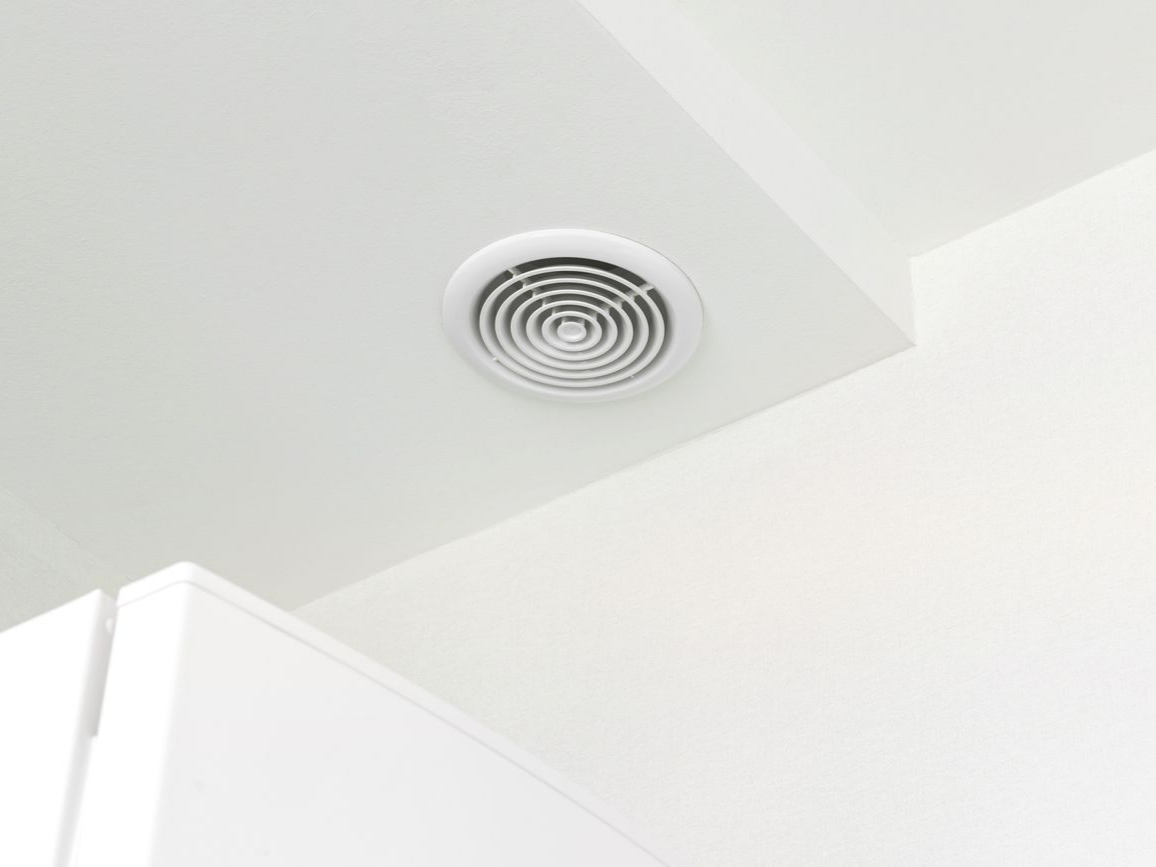 Plafond blanc avec une grille d'aération circulaire.