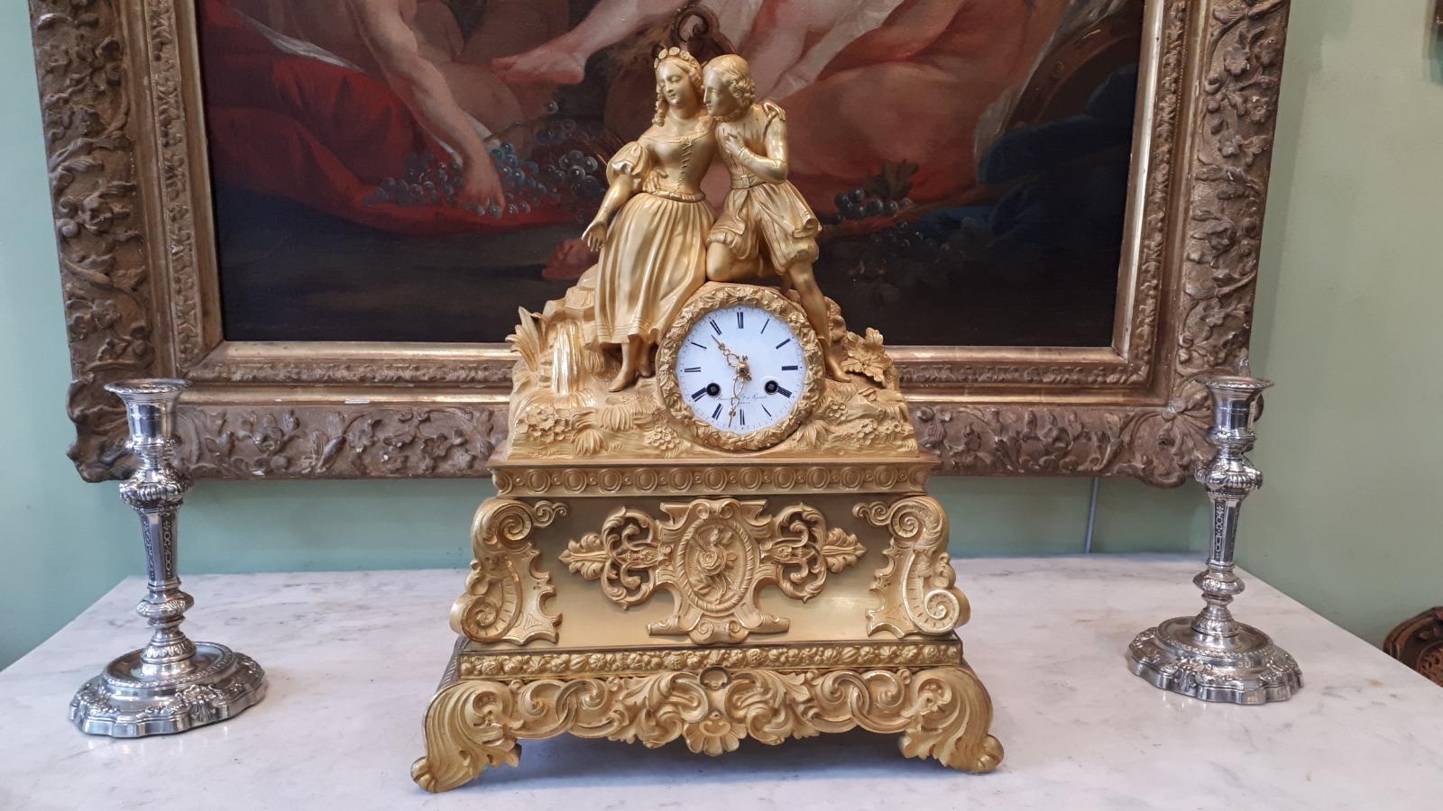 Horloge en métal doré avec deux statuettes dessus