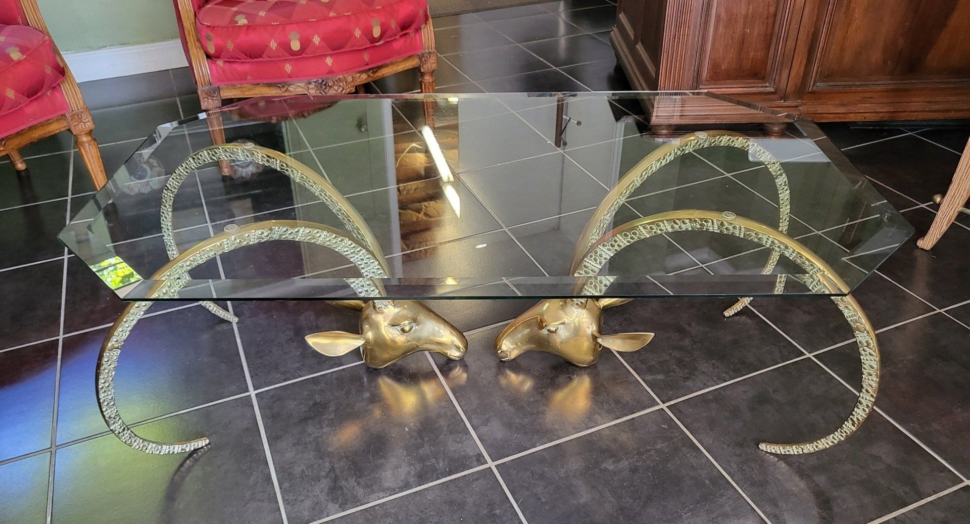 Table basse avec un plateau en verre et des pieds dorés en forme de tête d'animal