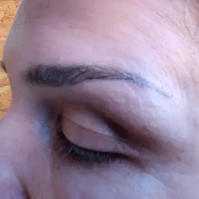 Un primer plano del ojo de una mujer con un tatuaje en la ceja.