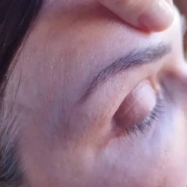 Un primer plano del rostro de una mujer con la mano en la frente.