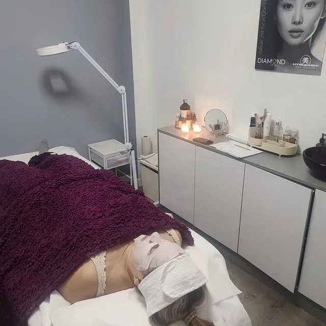 Una mujer está acostada en una cama con una manta morada y una máscara en la cara.