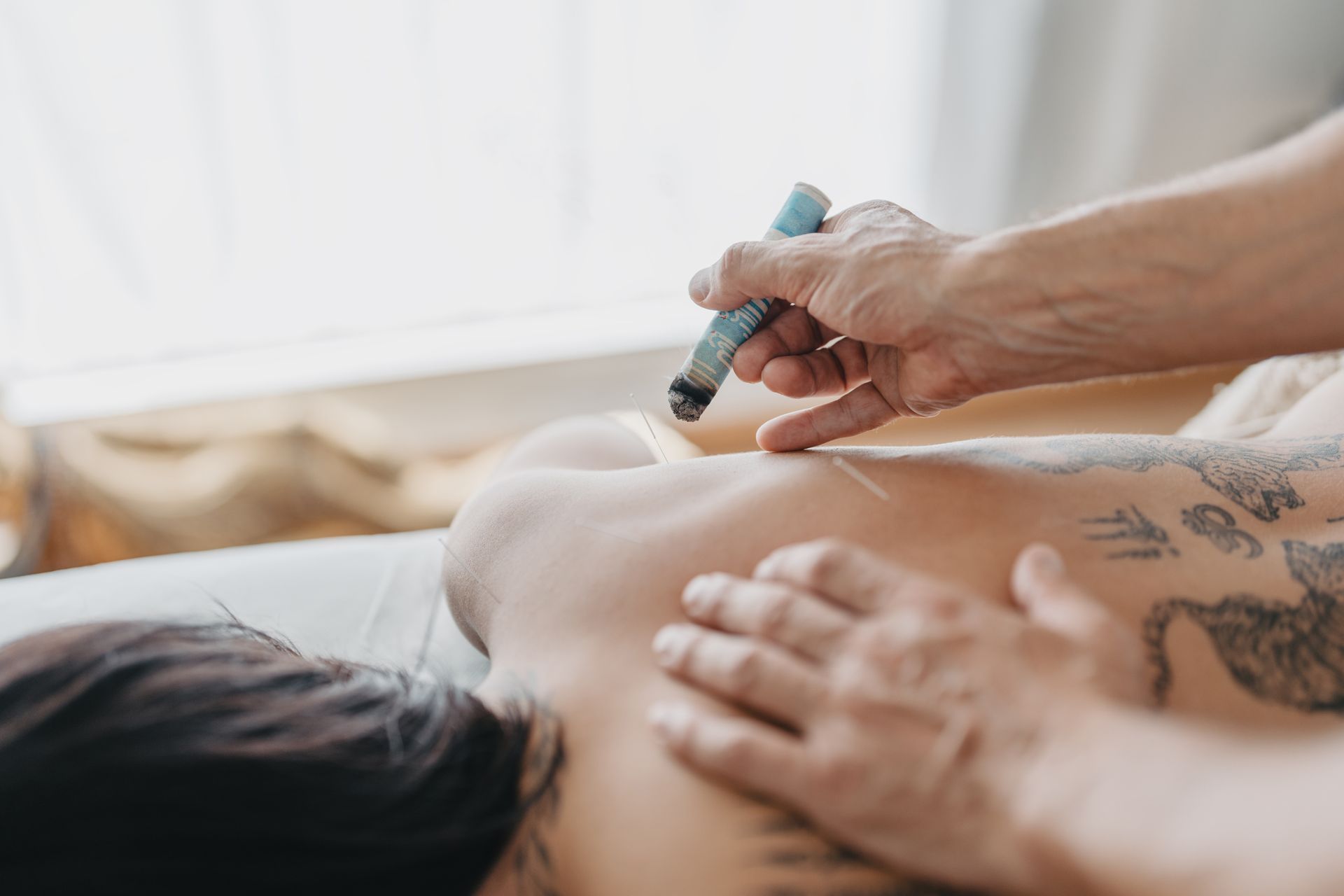 Hände benutzen ein beheiztes Massagegerät auf einem nackten Rücken während einer Spa-Behandlung