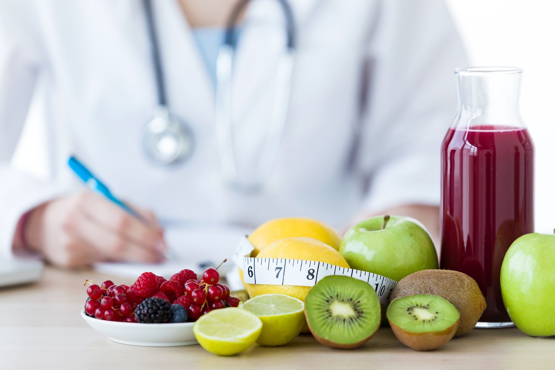 Nutritionniste avec fruits, jus et mètre ruban. Médecin écrivant, concept d'alimentation saine.