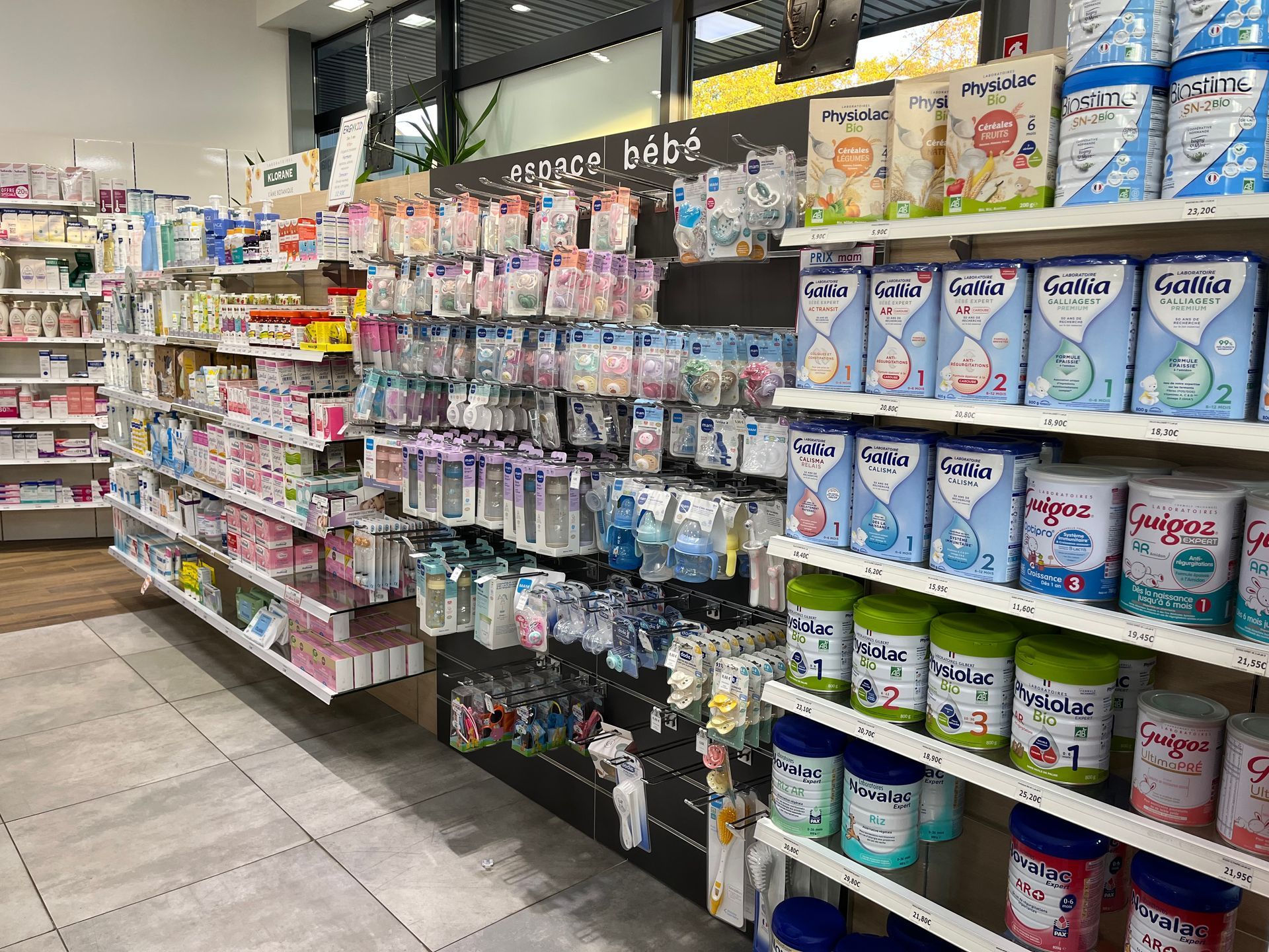 Étagères remplies de fournitures pour bébé dans une pharmacie, notamment du lait maternisé, des biberons et d'autres accessoires.