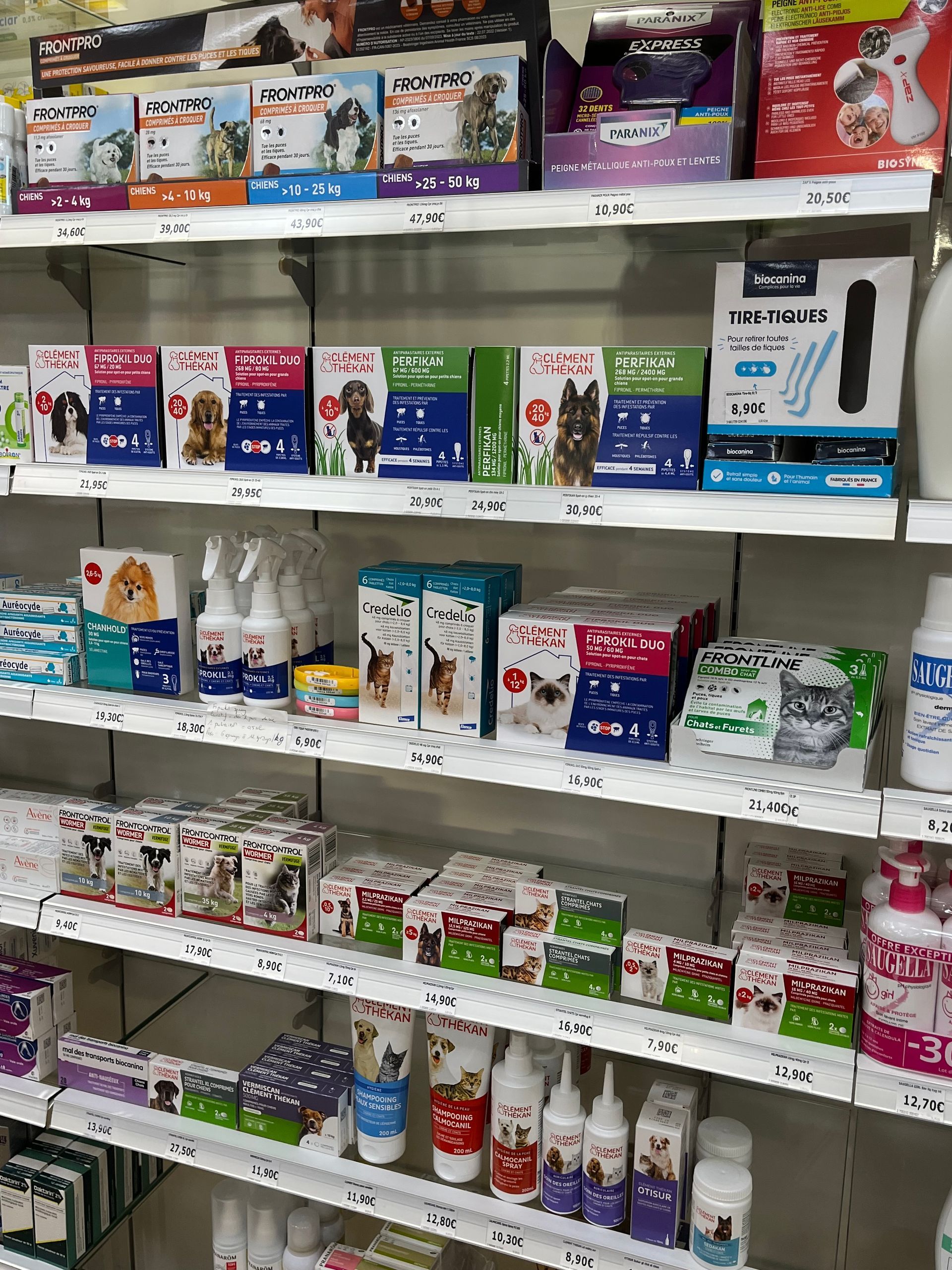 Étagères remplies de divers produits pour animaux de compagnie, notamment des aliments et des articles d'hygiène, dans un magasin.