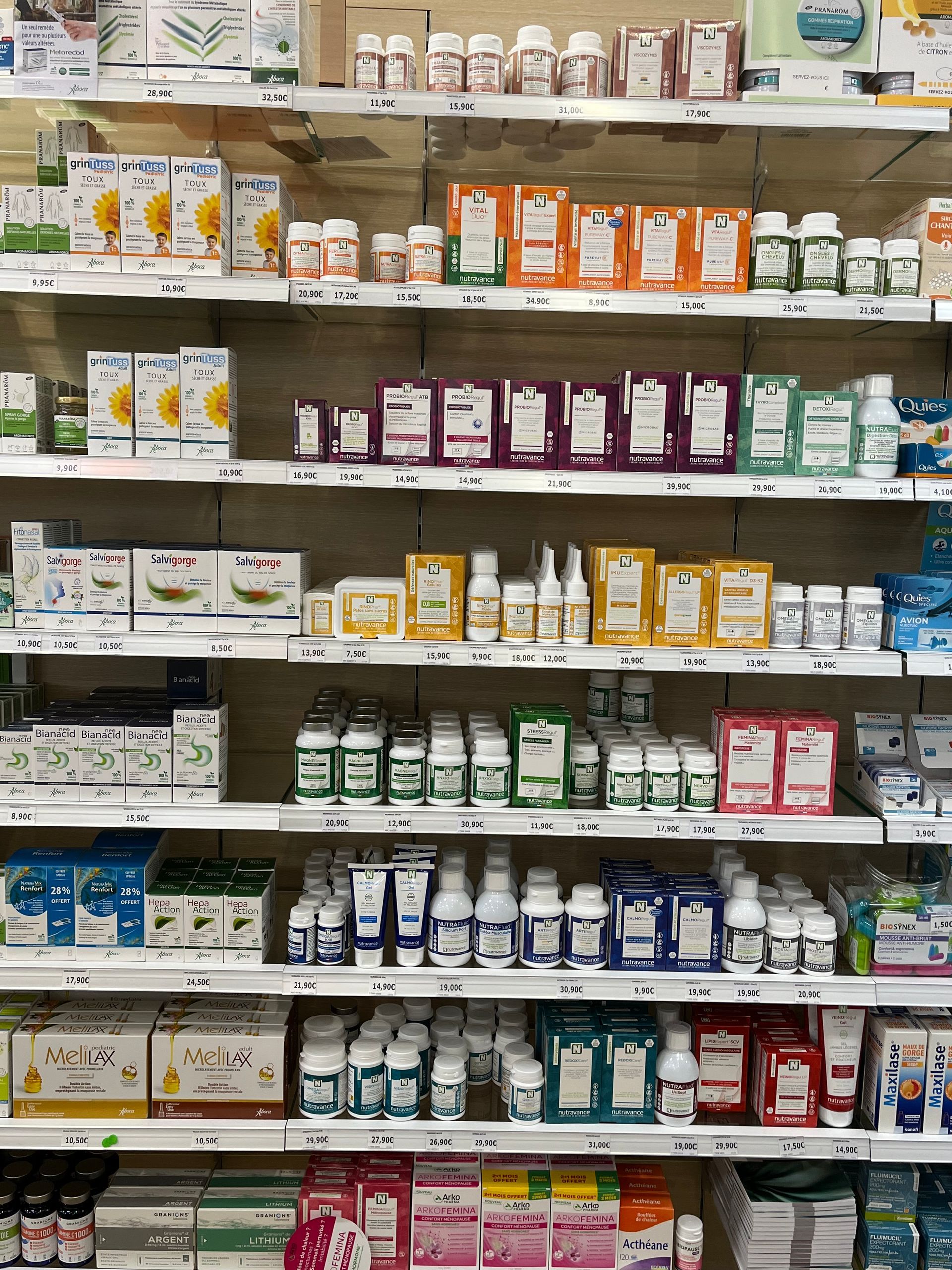 Étagères remplies de divers produits de santé et de bien-être dans une pharmacie.