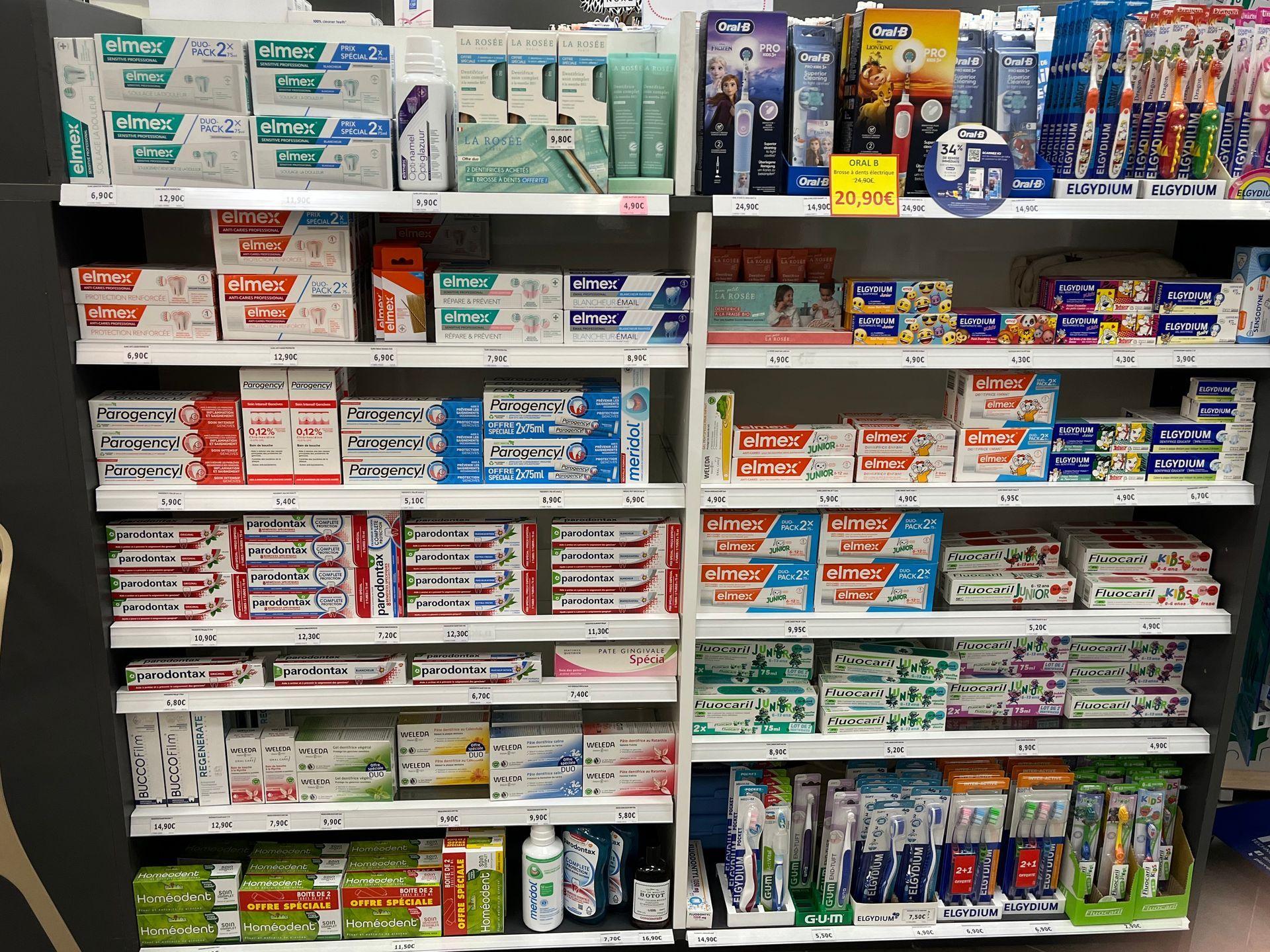 Étagères remplies de divers dentifrices et produits d'hygiène bucco-dentaire dans un magasin.