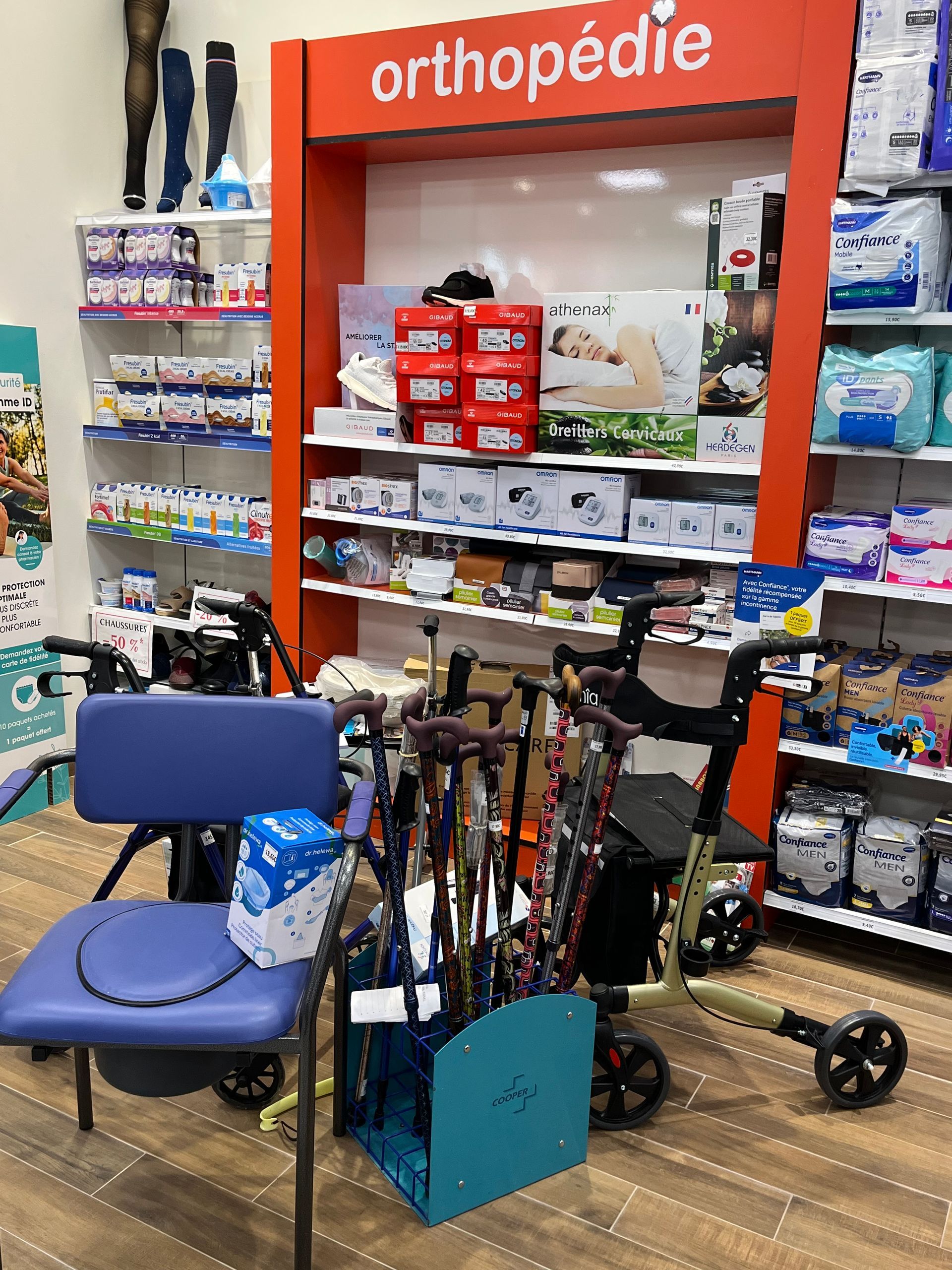 Présentoir de pharmacie : aides à la marche, aide à l'assise, étagères de fournitures médicales étiquetées « orthopédie ».