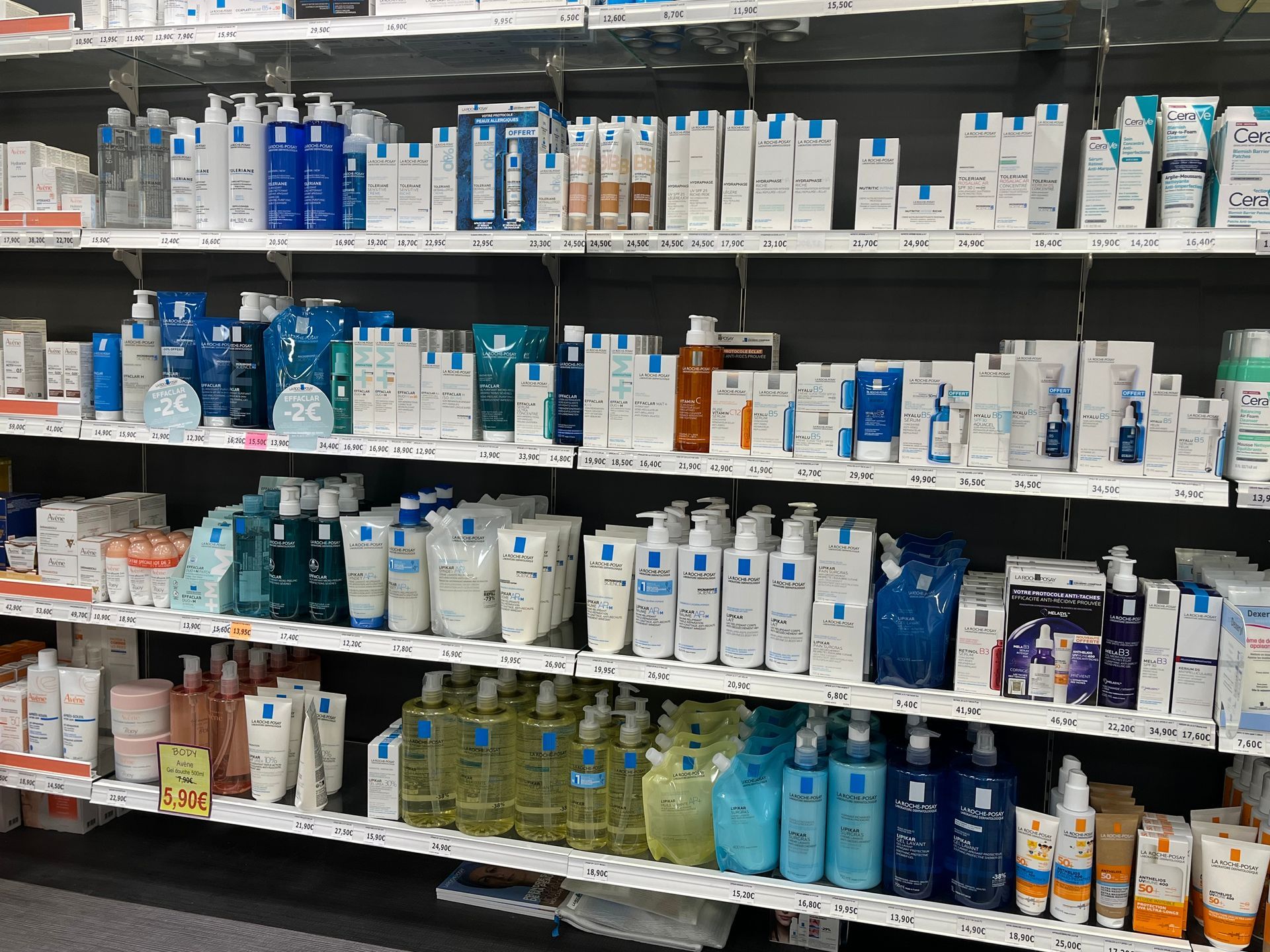 Des étagères remplies de divers produits de soins de la peau dans des emballages blancs, bleus et transparents.