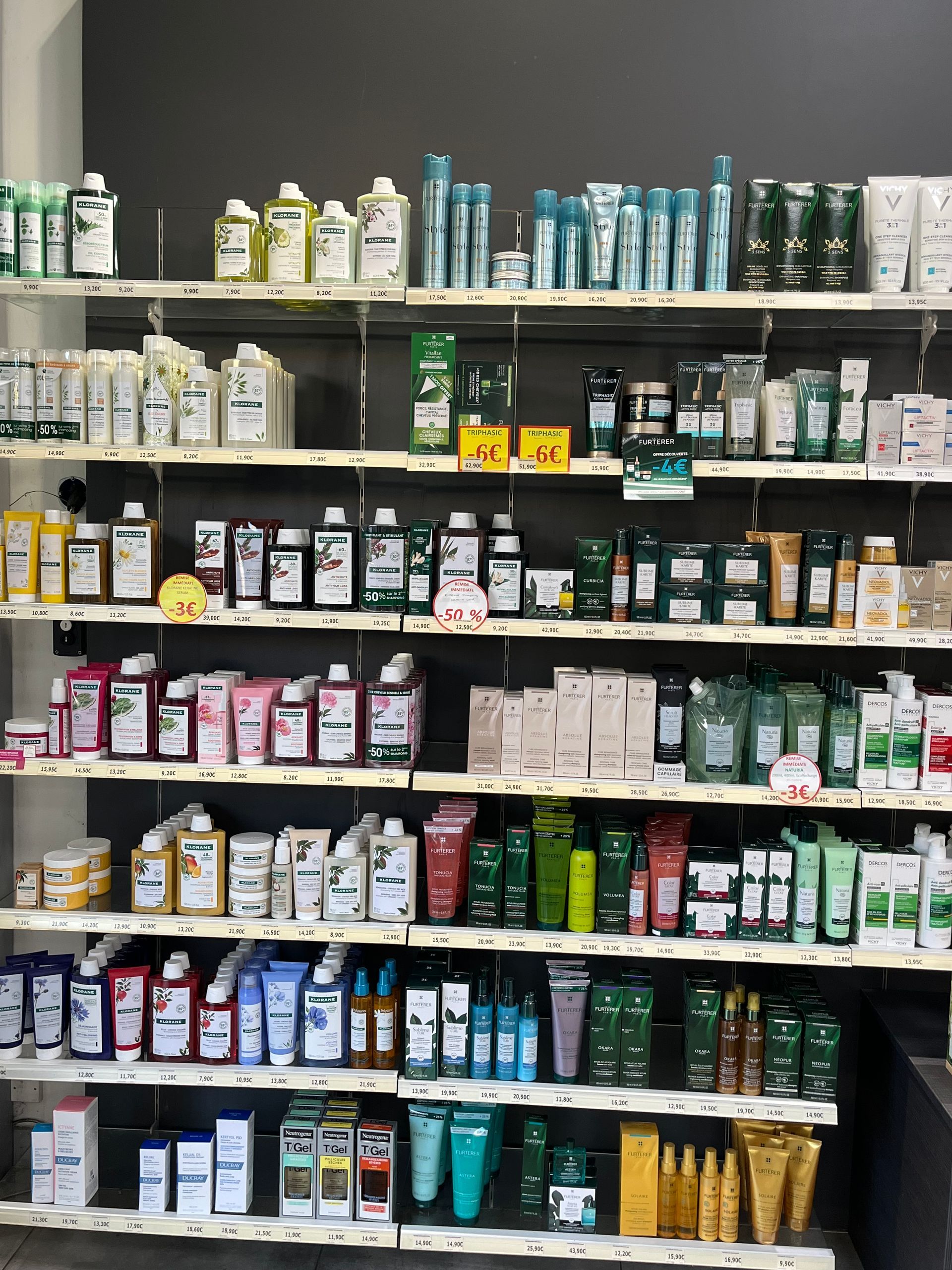 Étagères remplies de divers produits cosmétiques dans un magasin ; bouteilles, tubes et contenants de différentes couleurs.