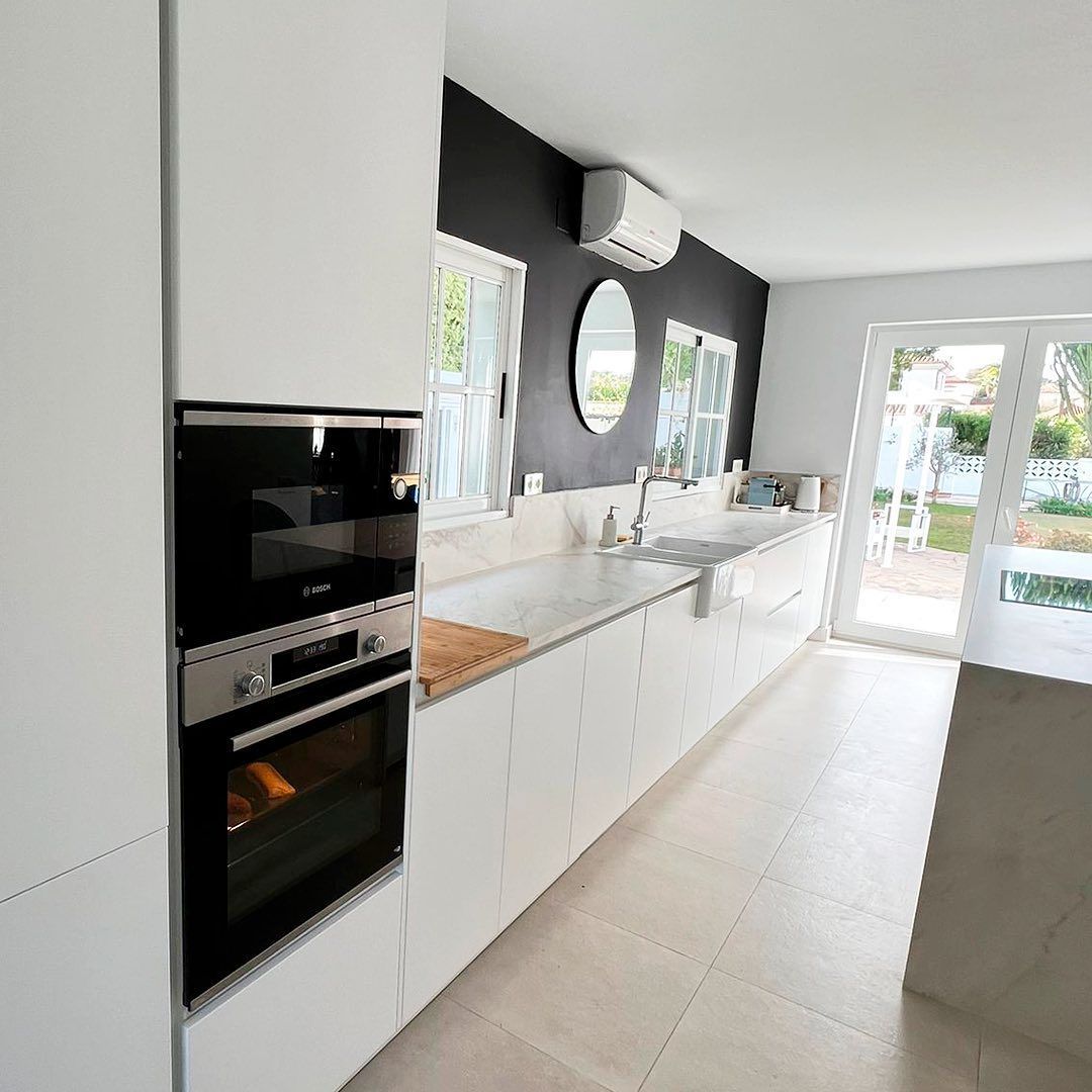 Una cocina con gabinetes blancos y un horno negro.