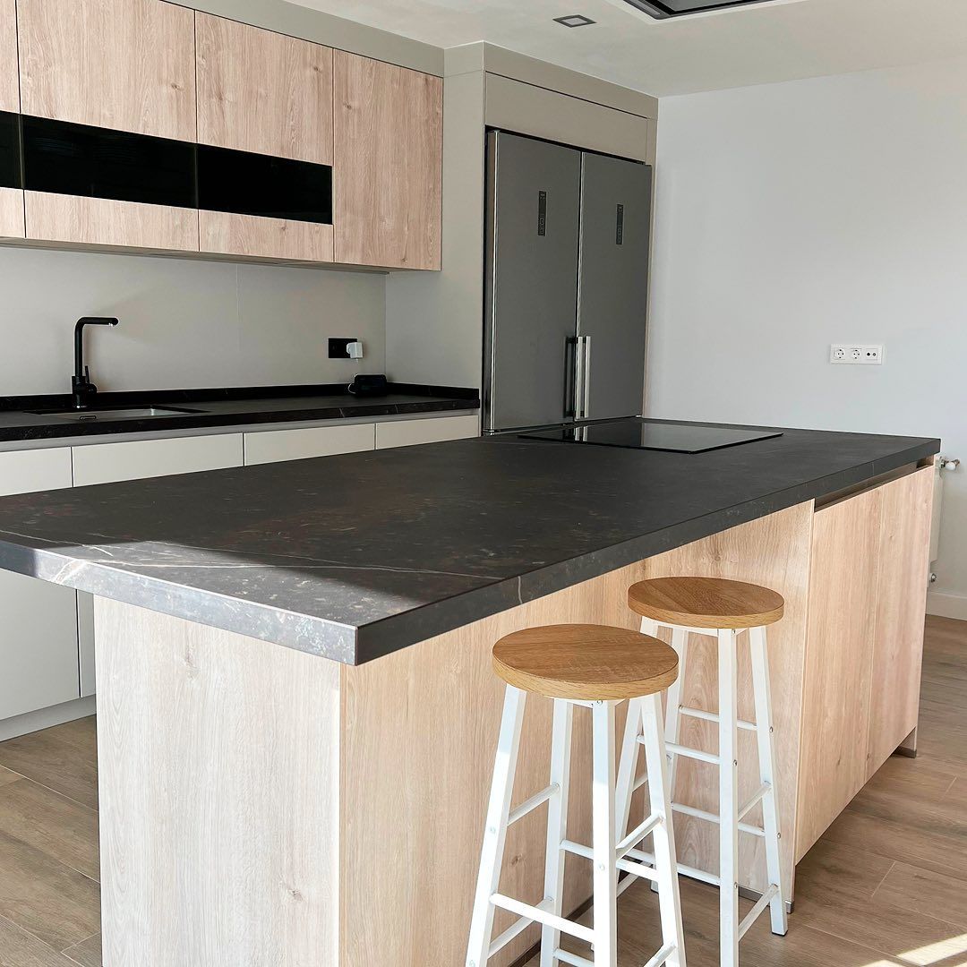 Una cocina con una gran isla y dos taburetes.