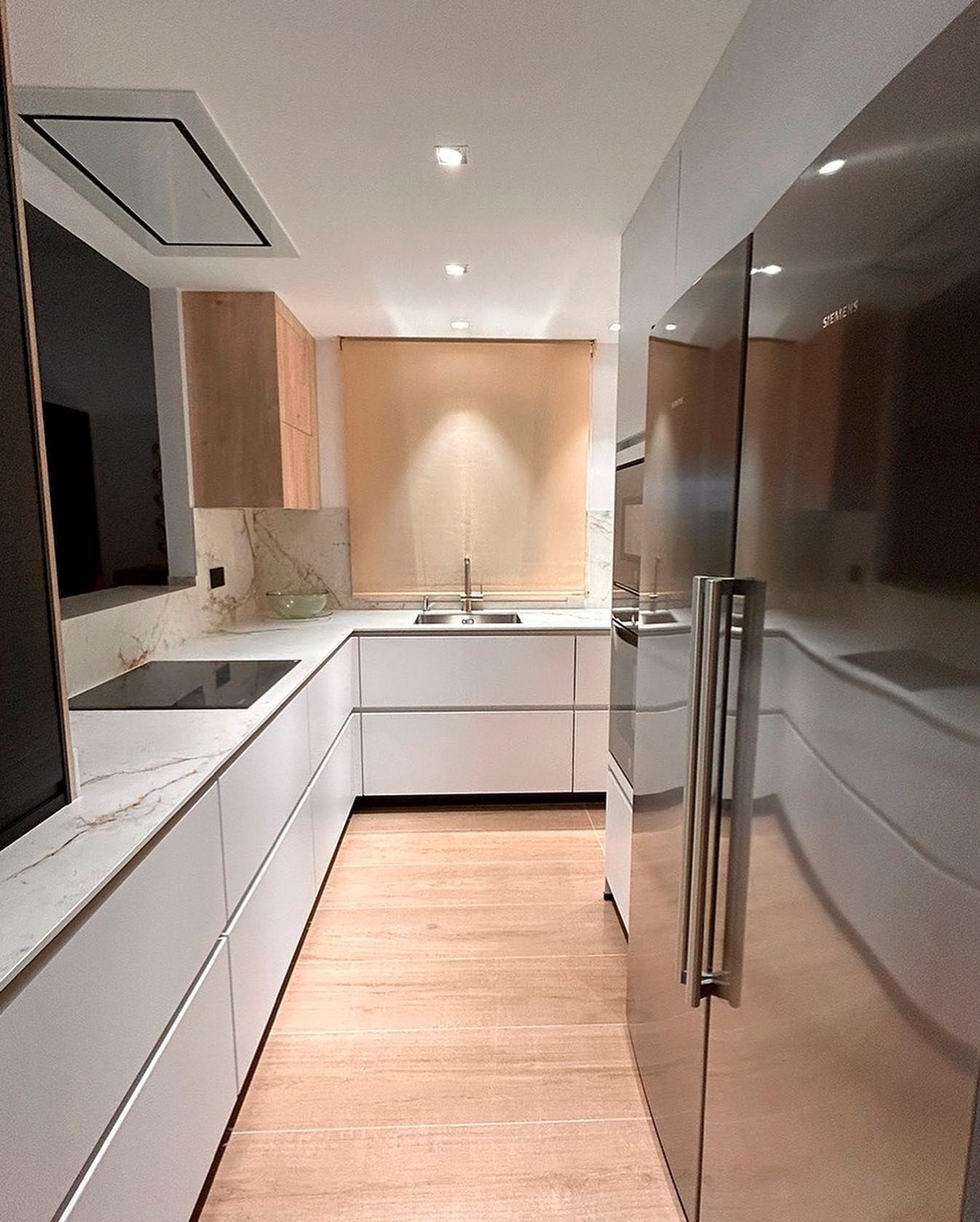Una cocina con gabinetes blancos y electrodomésticos de acero inoxidable.