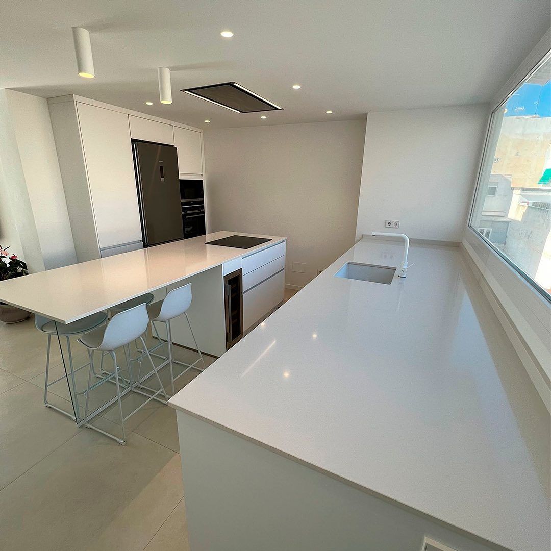 Una cocina con una mesa y sillas y un fregadero.