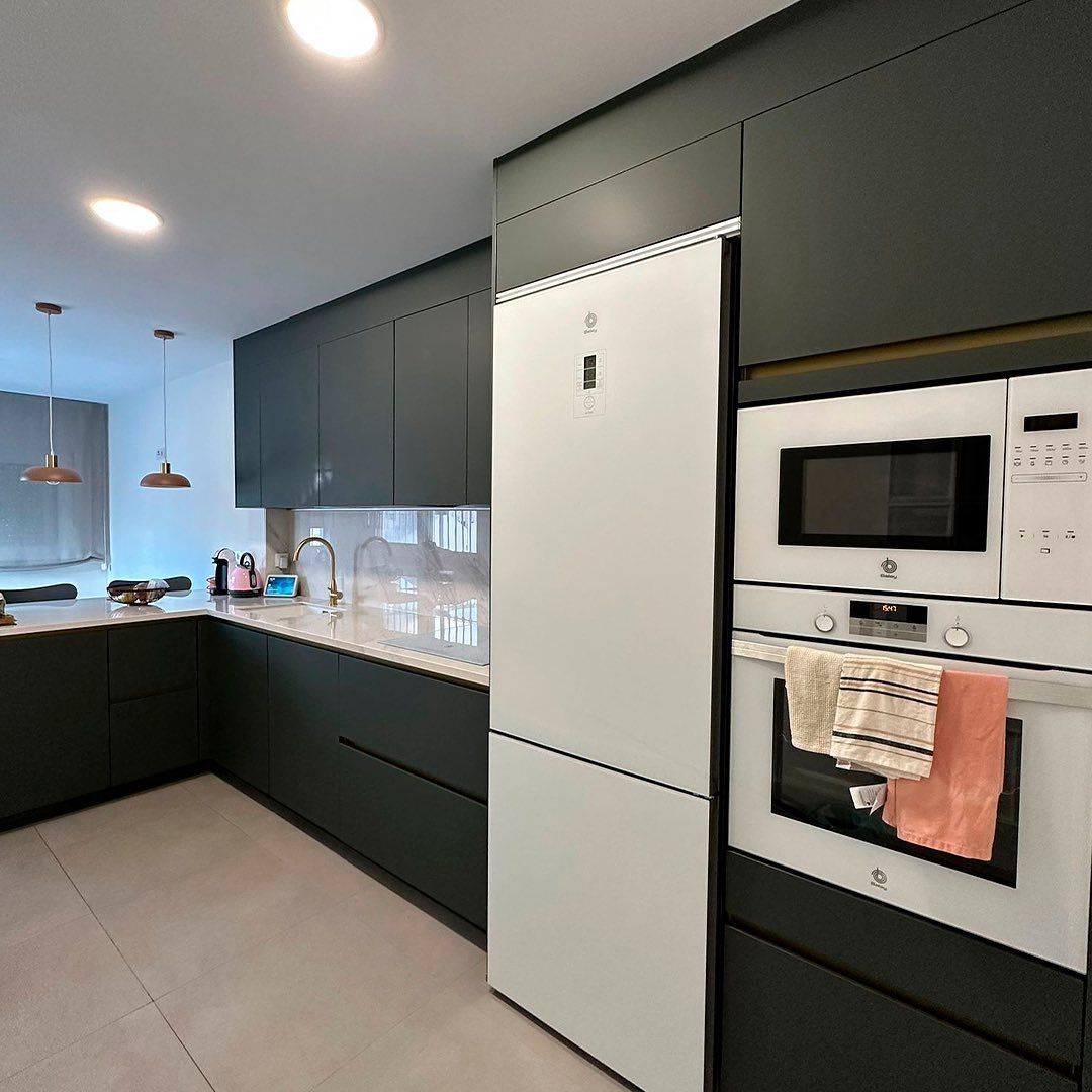 Una cocina con gabinetes negros y electrodomésticos blancos.