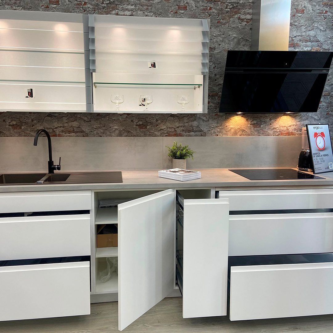 Una cocina con gabinetes blancos, un fregadero y una estufa.