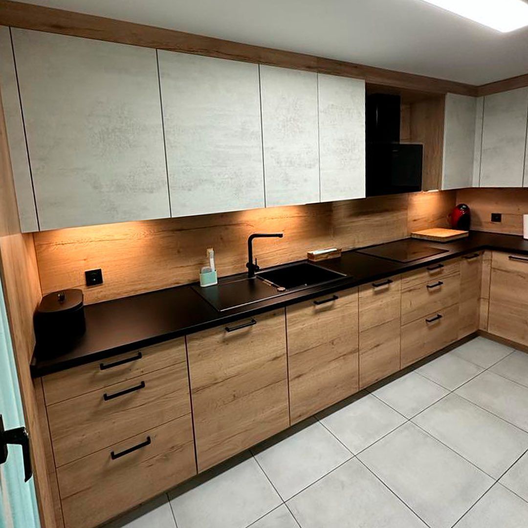 Una cocina con gabinetes de madera, encimeras negras y un fregadero.
