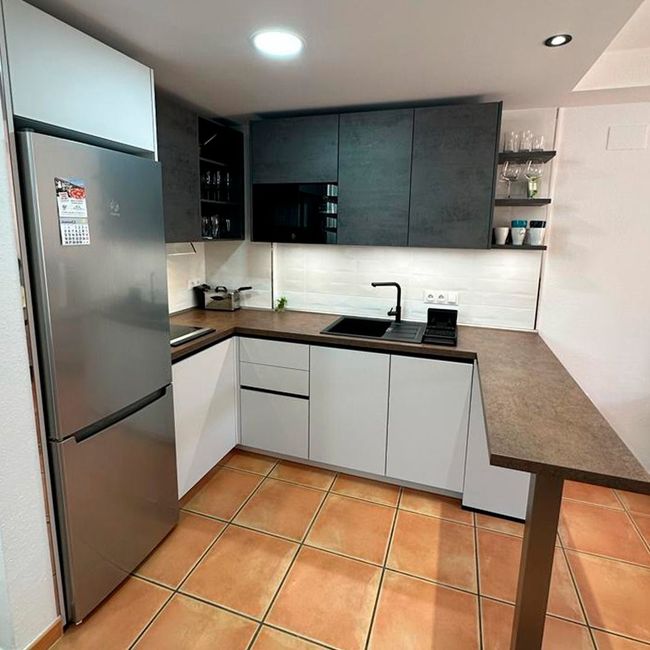 Una cocina con gabinetes blancos y un refrigerador de acero inoxidable.