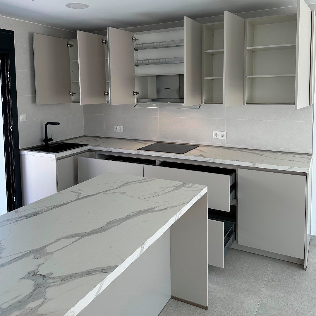 Una cocina con gabinetes blancos y encimera de mármol.