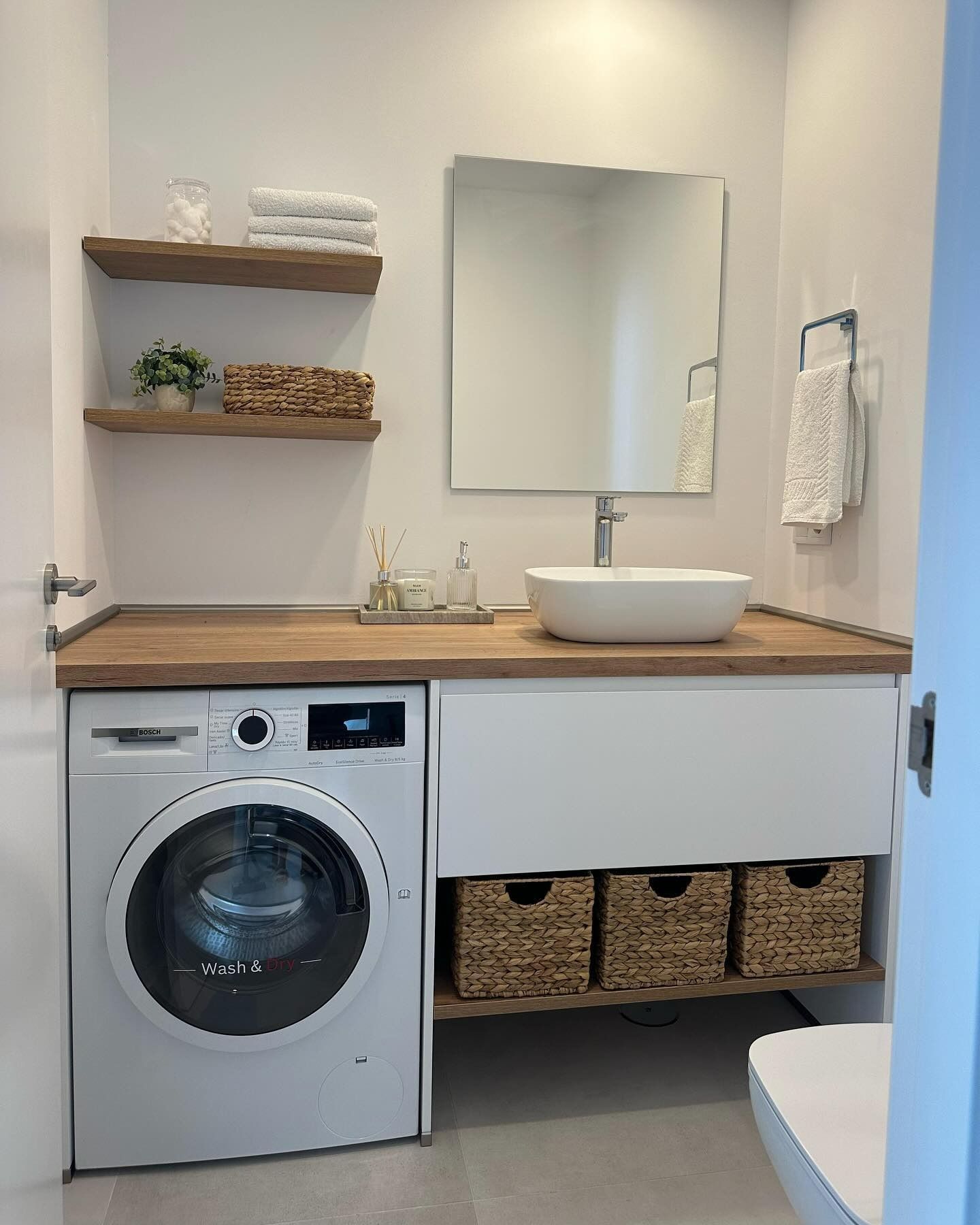 Un baño con lavadora, lavabo y espejo.