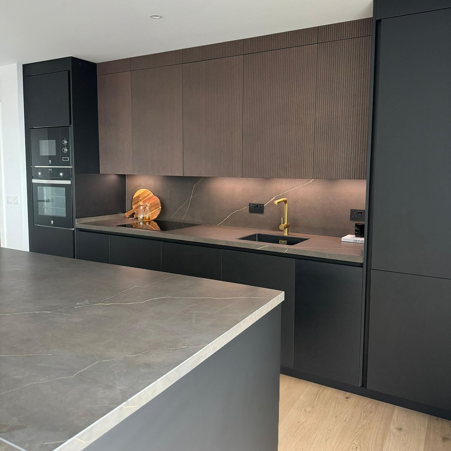Una cocina con gabinetes negros y encimera de mármol.