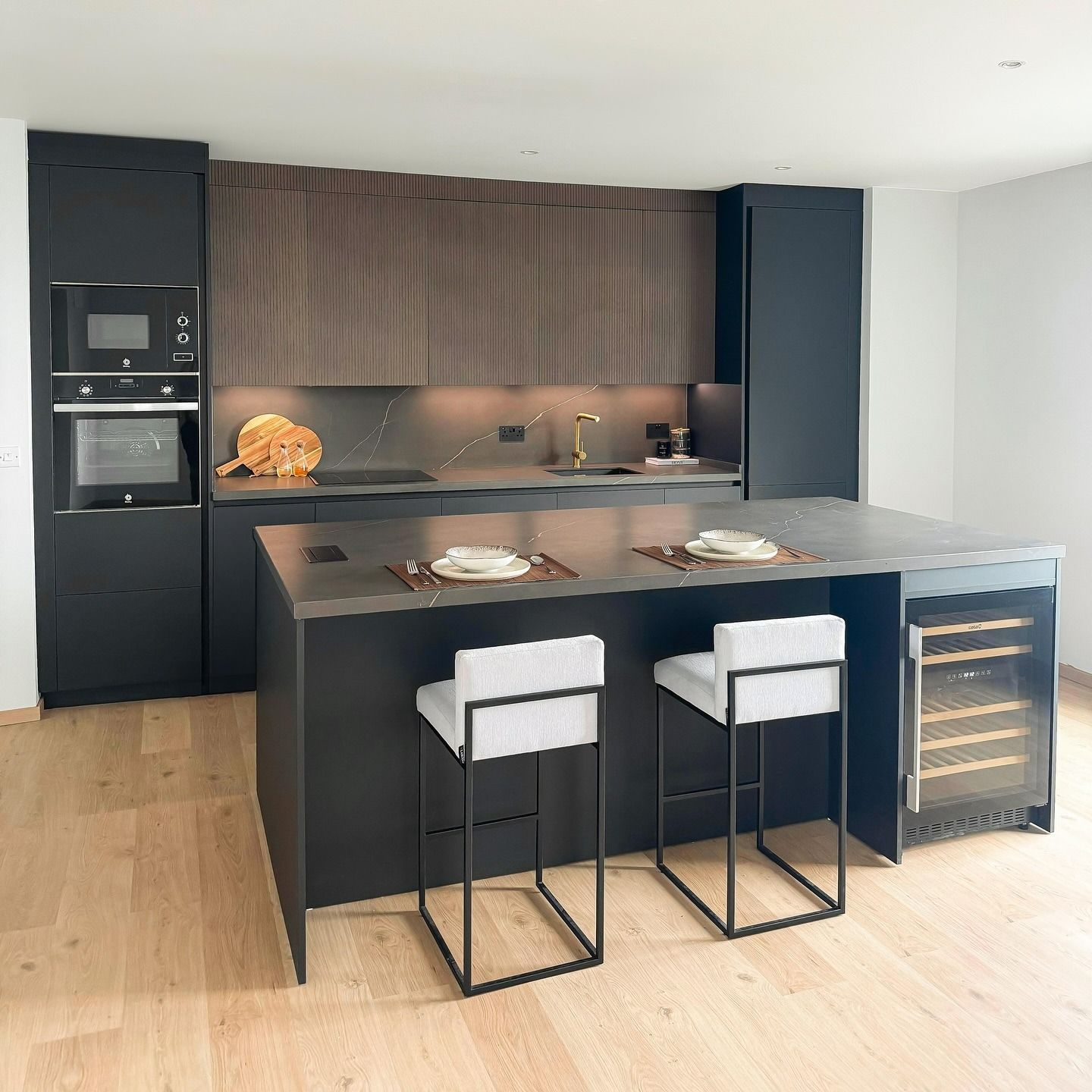 Una cocina con una gran isla y dos taburetes.