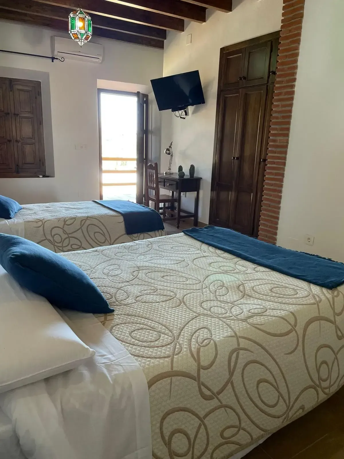 Una habitación de hotel con dos camas y un televisor en la pared.