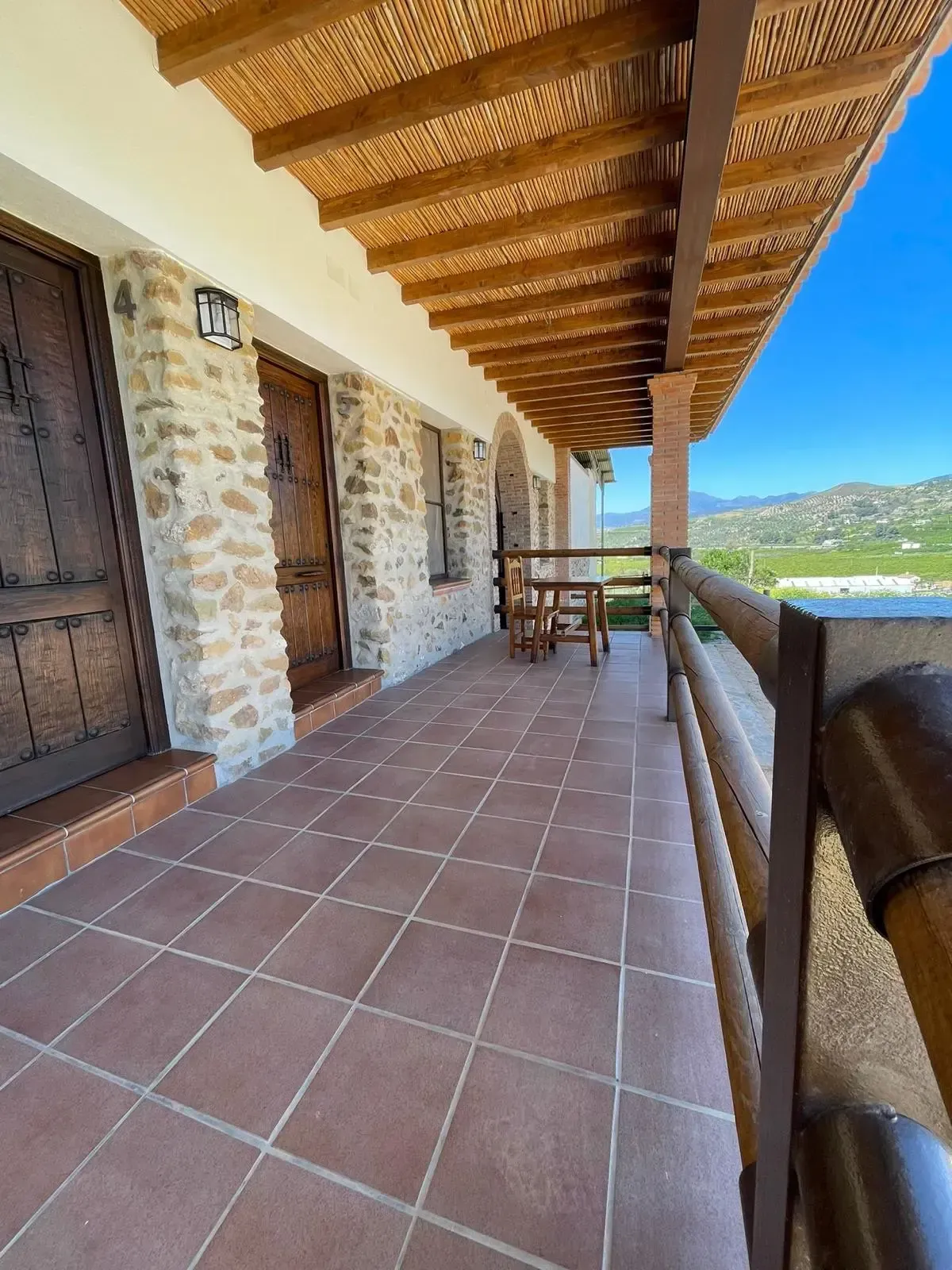 Un gran porche con barandilla de madera y una mesa y sillas encima.