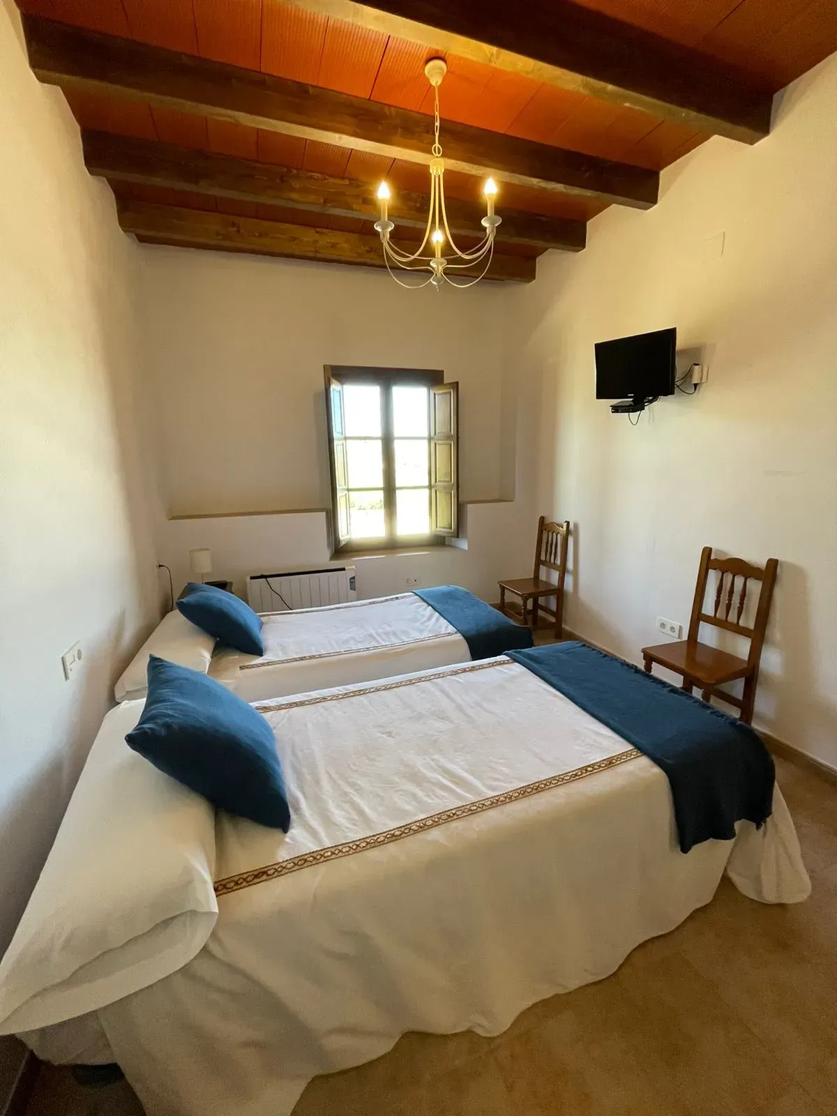 Un dormitorio con dos camas y un televisor en la pared.