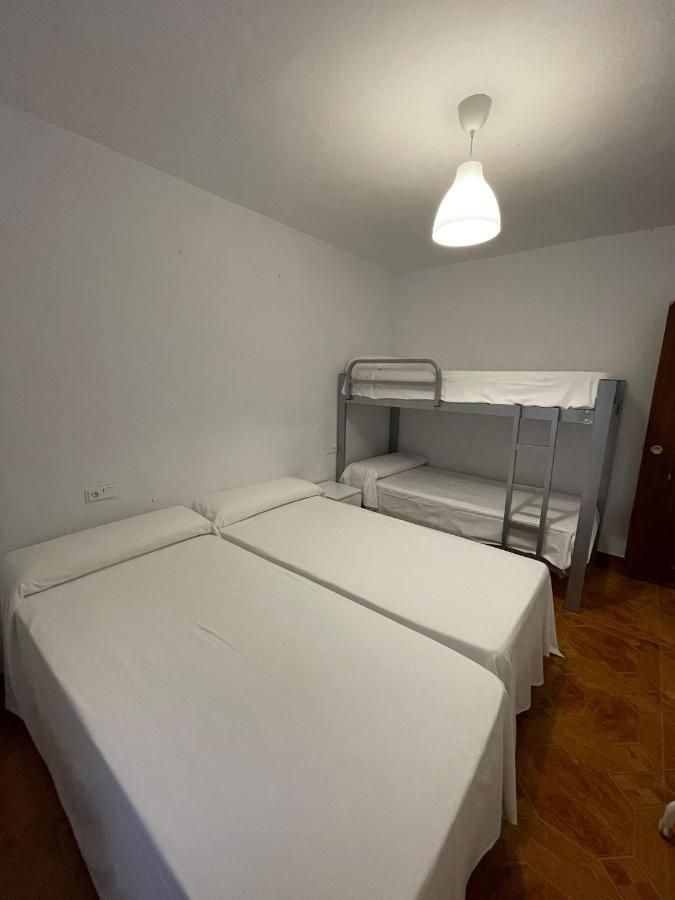 Un dormitorio con tres literas y una lámpara de techo.