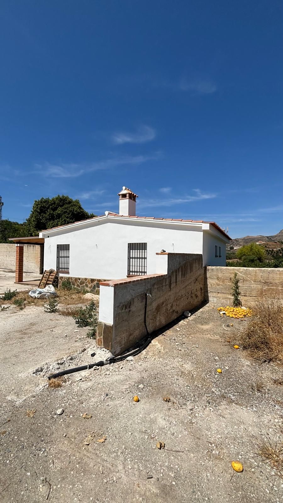 Una casa blanca está situada en medio de un campo de tierra.
