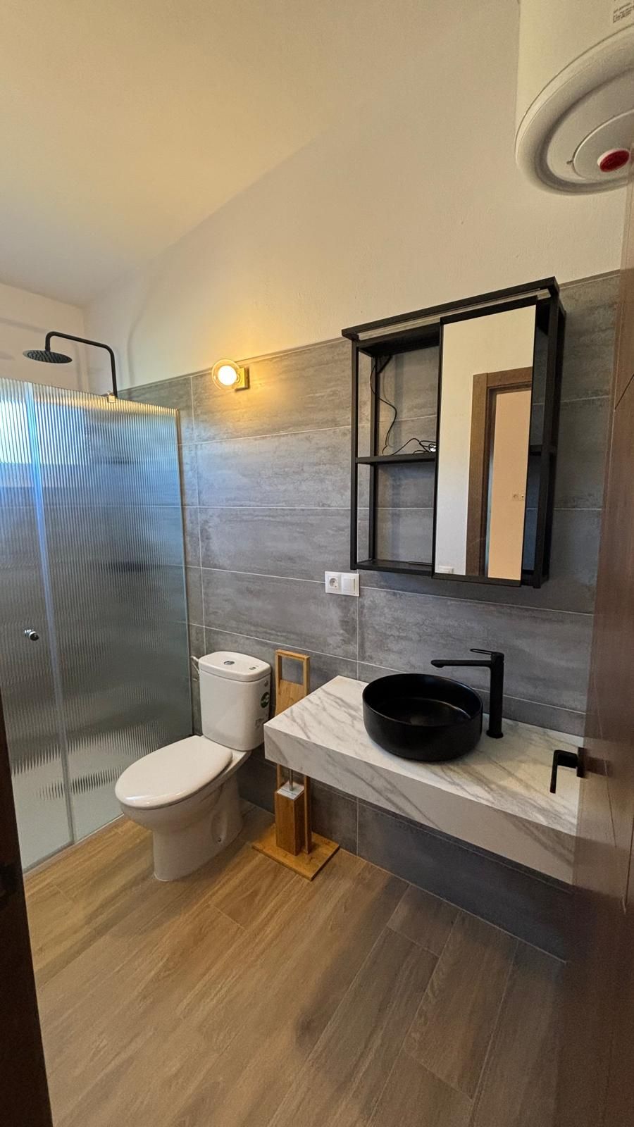 Un baño con inodoro, lavabo, ducha y espejo.