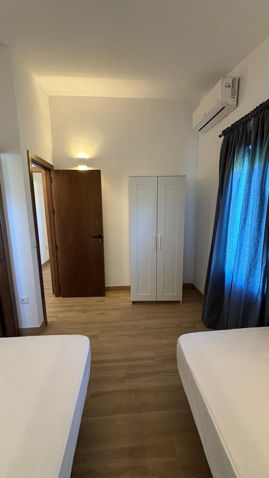 Un dormitorio con dos camas, un armario y una ventana.