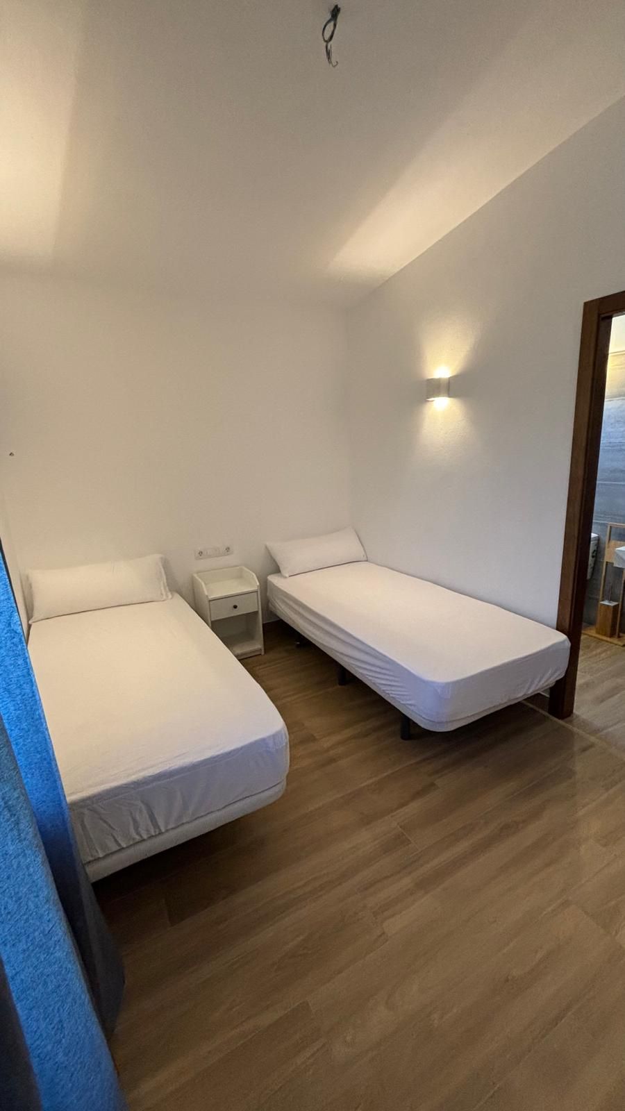 Un dormitorio con dos camas y una mesita de noche.