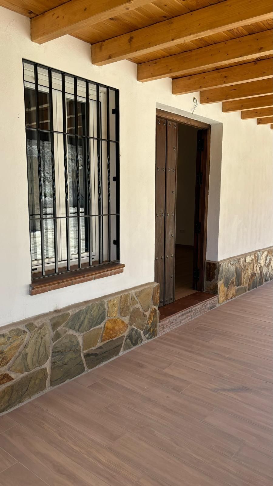 Un edificio blanco con un techo de madera y una ventana con rejas.