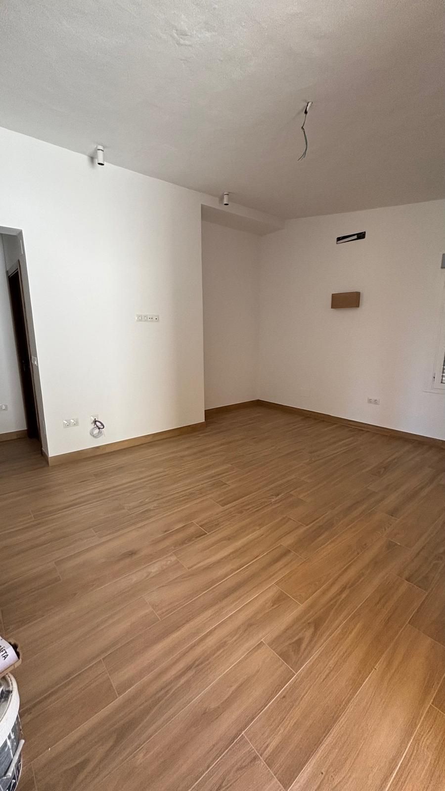 Una habitación vacía con suelos de madera y paredes blancas.