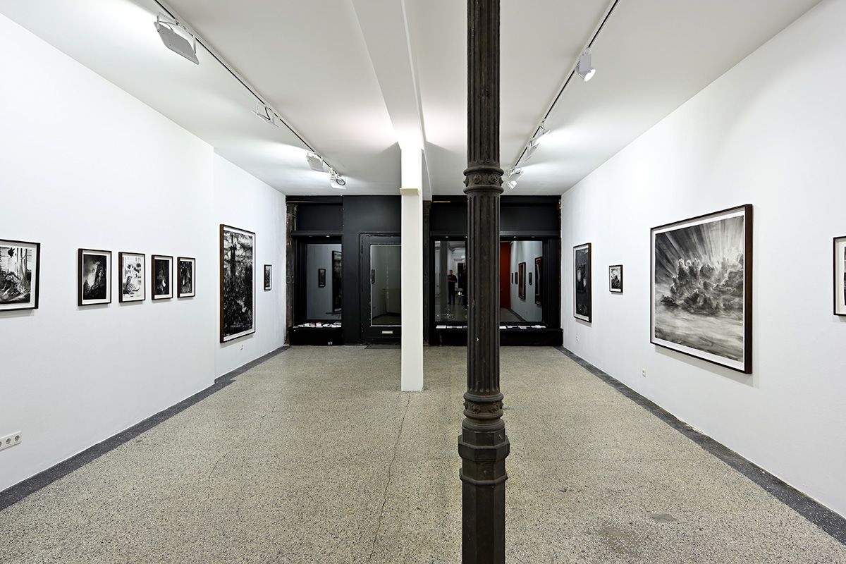 Ein großer Raum mit einer Säule in der Mitte und vielen Bildern an der Wand.