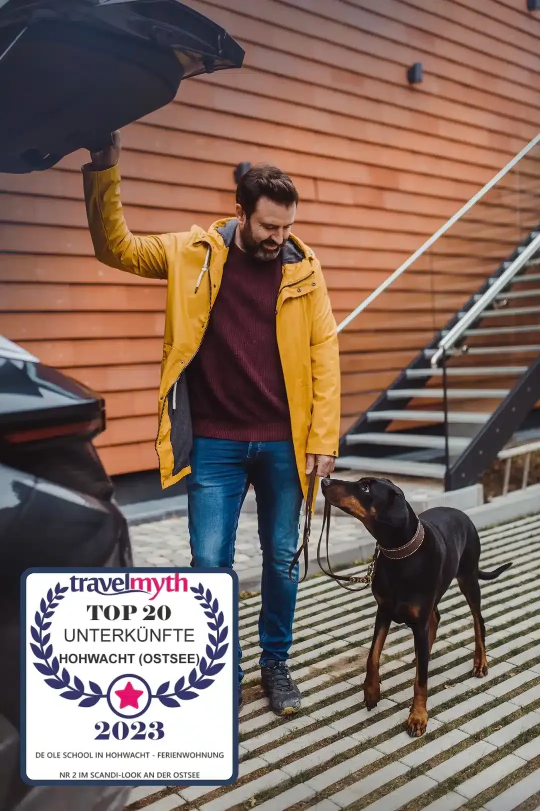 Ein Mann steht mit seinem Hund neben einem Auto.