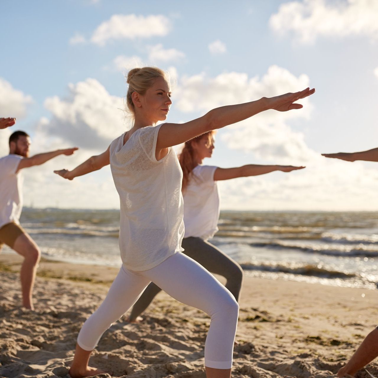 A group of people are practicing yoga on the beach