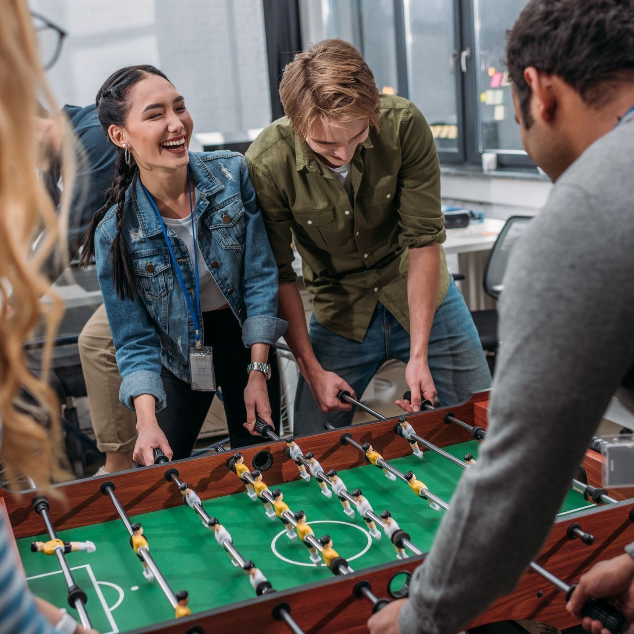 A group of people are playing a foosball game together.