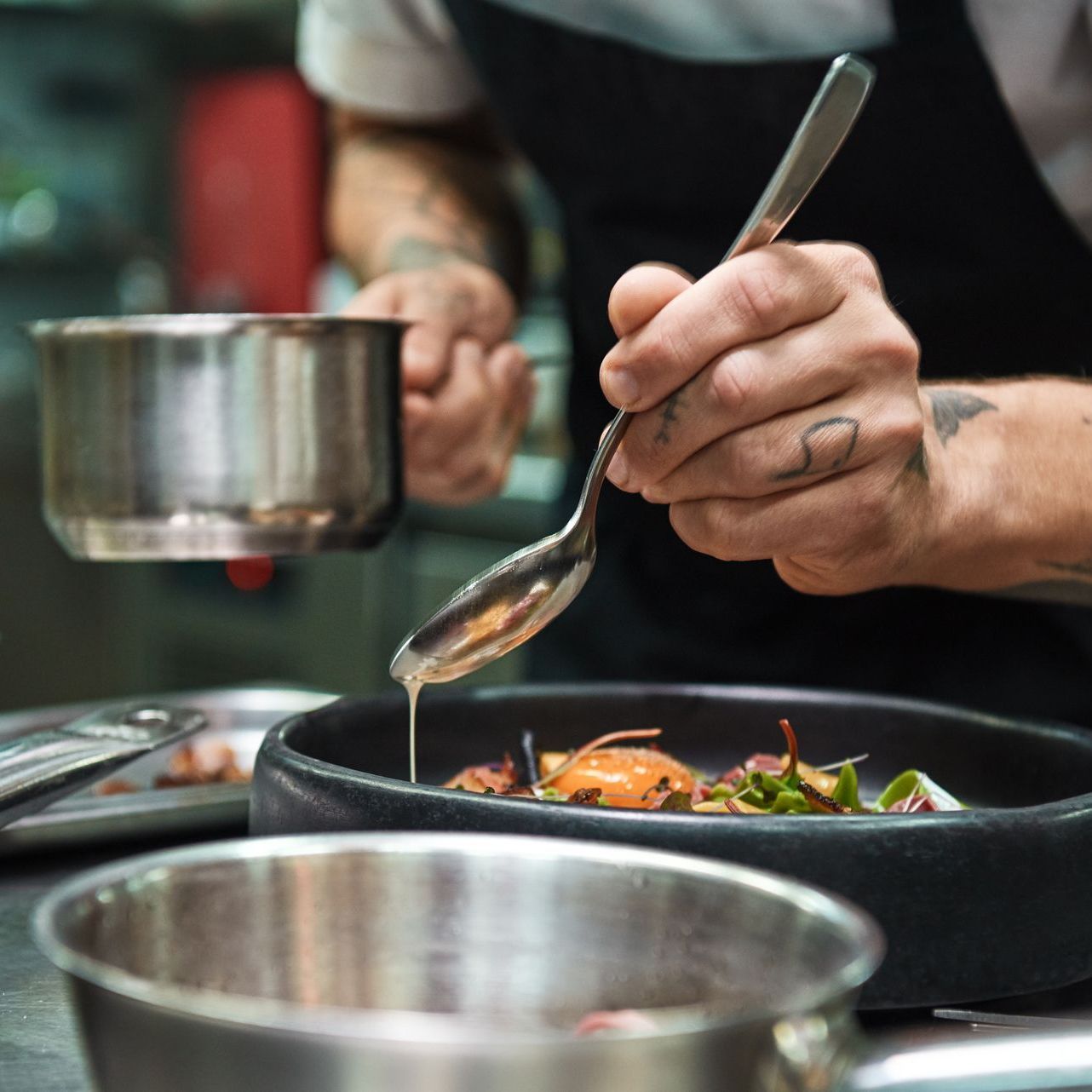 A person is holding a spoon over a pan of food