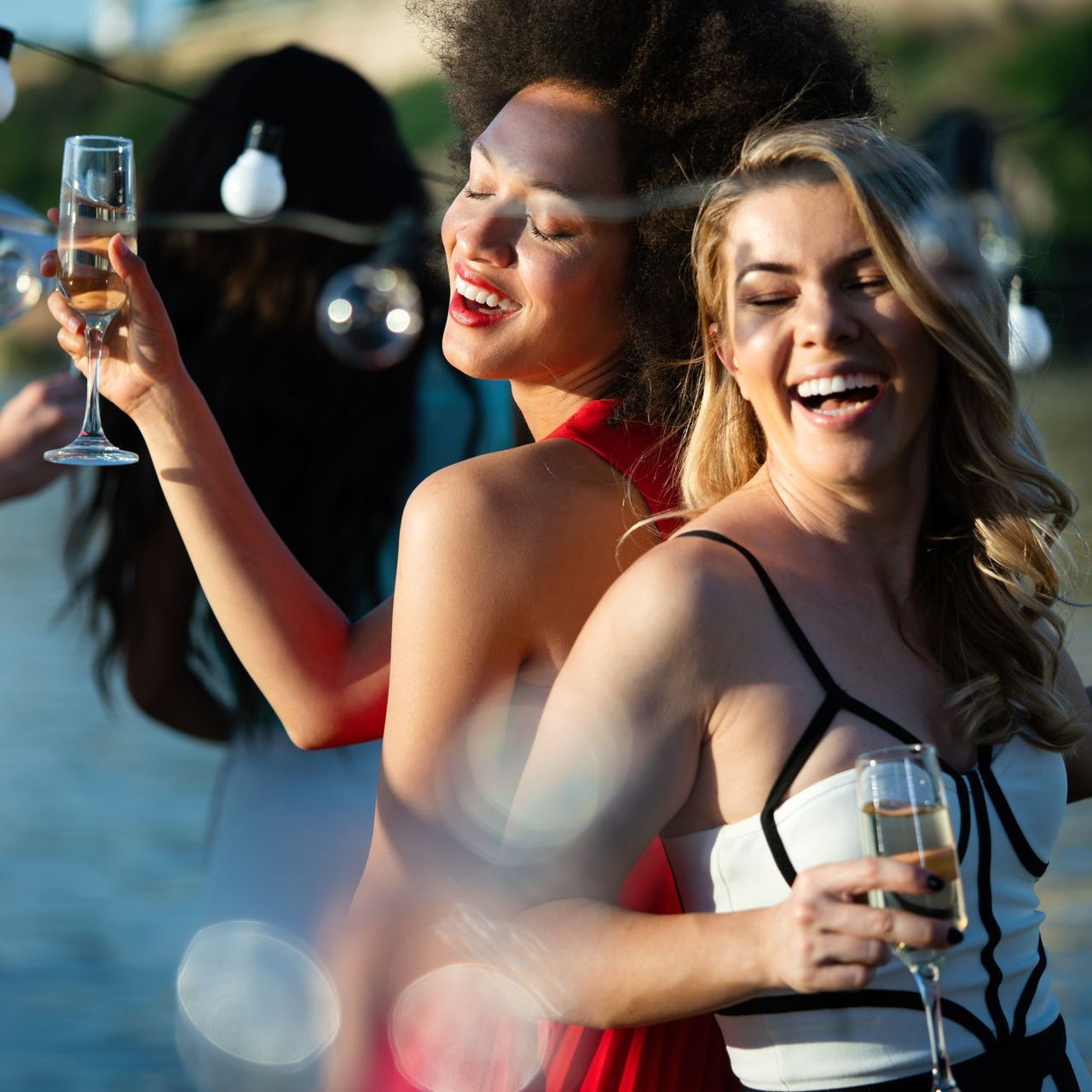 Zwei Frauen halten Sektgläser, lachen und feiern Party.