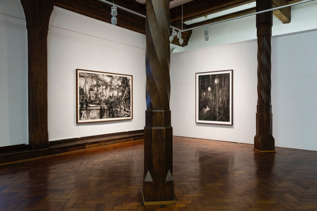 Ein Raum mit zwei Gemälden an der Wand und einem Holzboden.