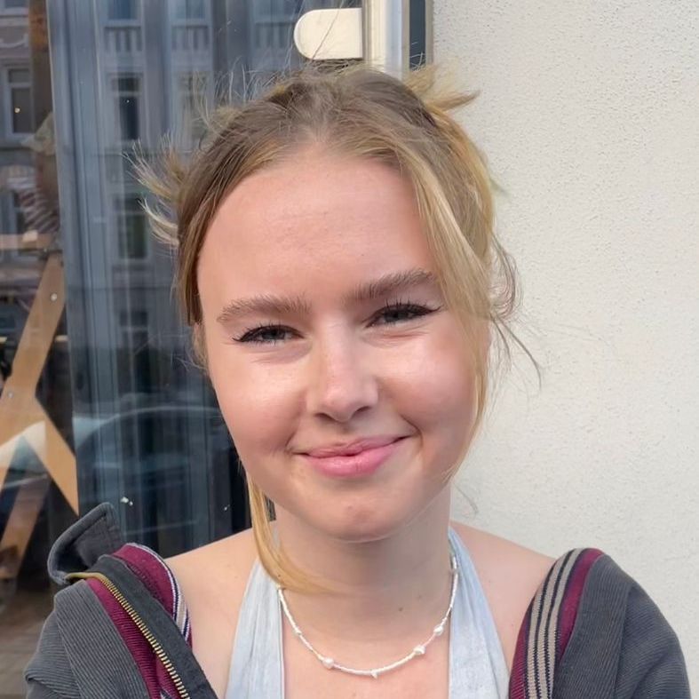 A woman wearing a necklace smiles for the camera