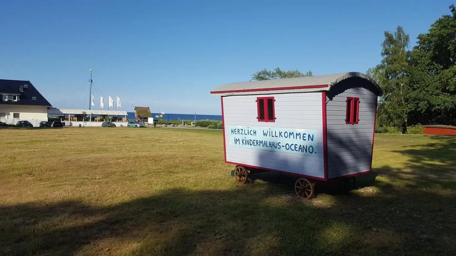 Ein kleiner weiß-roter Wagen steht auf einer Wiese.