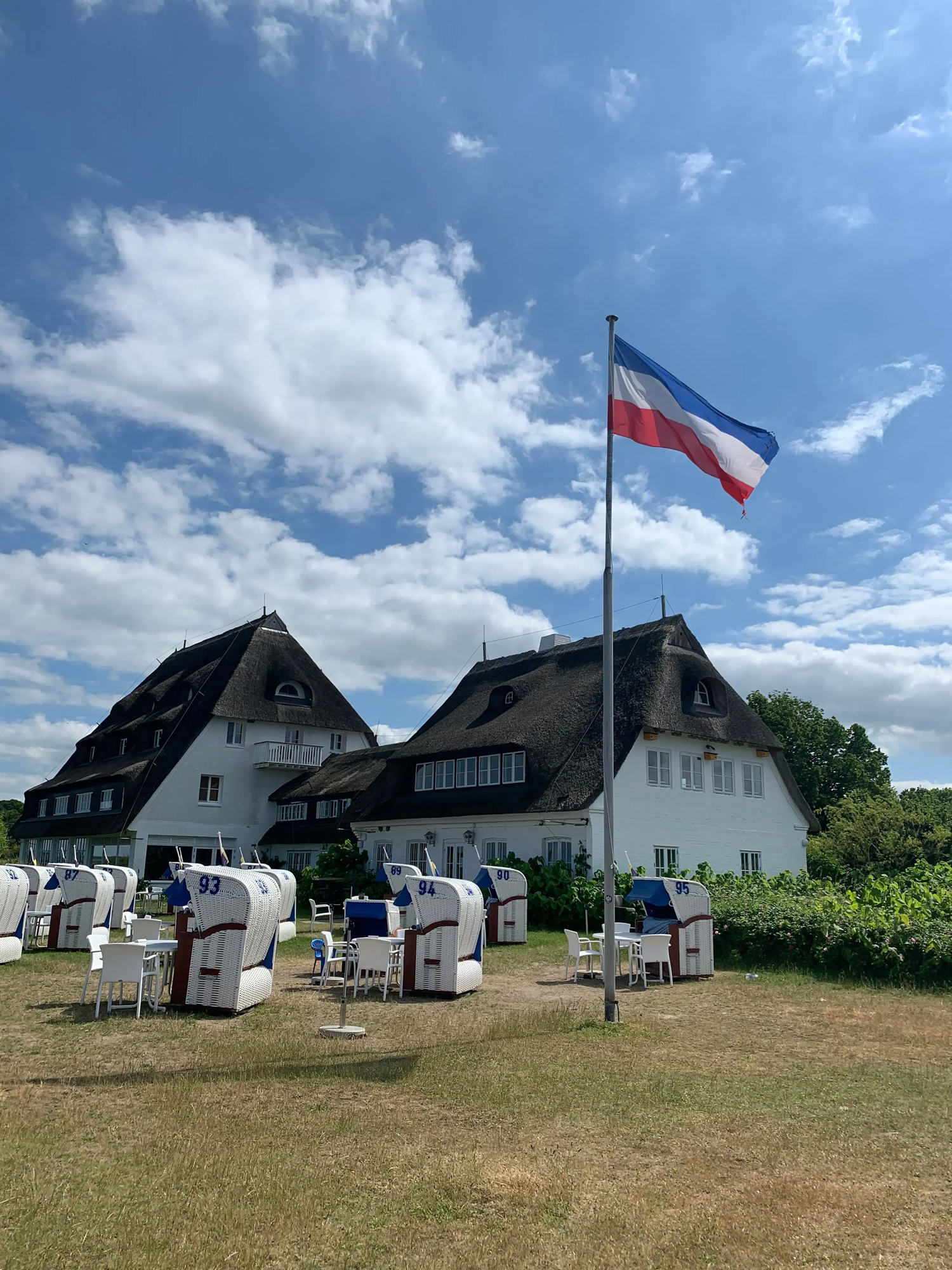 Ein Haus, in dem sich ein Restaurant in Hohwacht befindet mit einer Reihe Strandkörben davor.